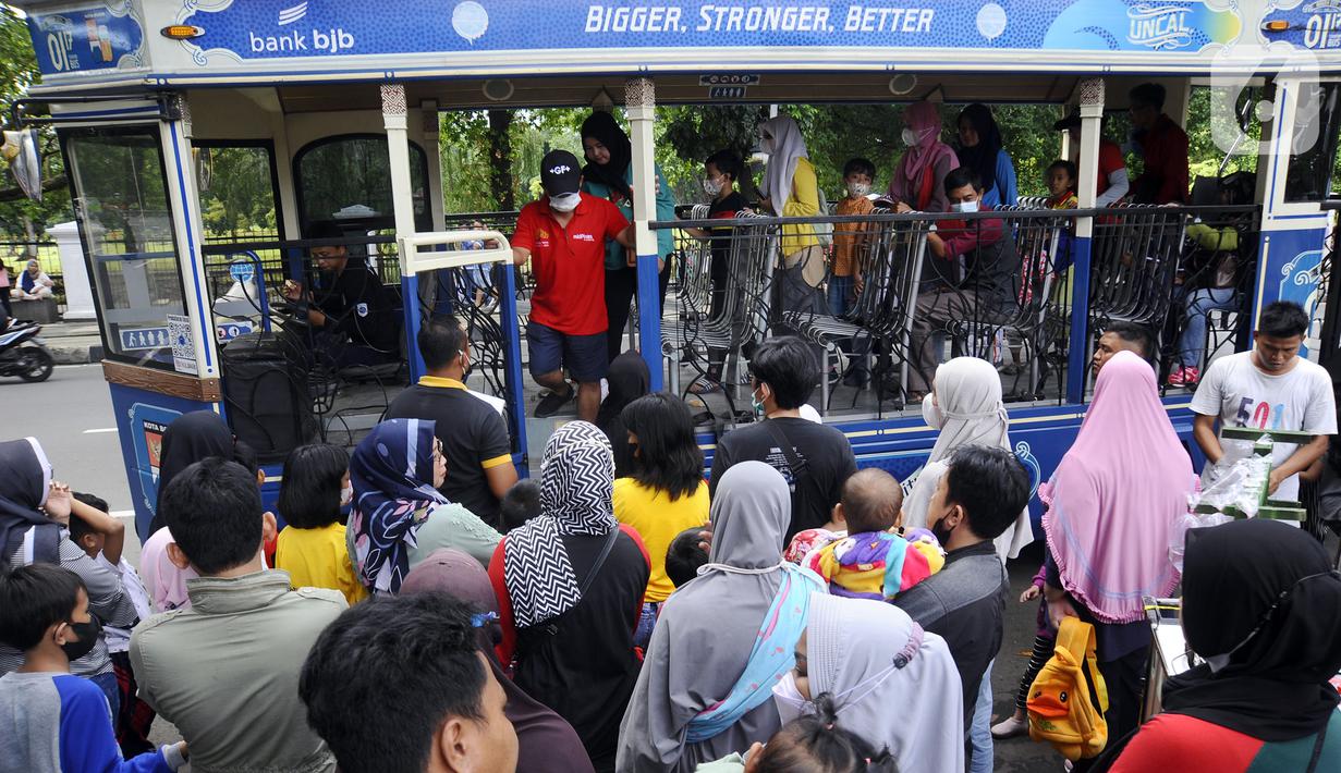 Warga antre masuk bus wisata Uncal di depan Balai Kota Bogor, Bogor, Jawa Barat, Minggu (29/5/2022). Bus wisata gratis yang disediakan untuk mengelilingi kawasan Kebun Raya Bogor setiap hari Sabtu dan Minggu ini mulai beroperasi kembali pascapandemi. (merdeka.com/Arie Basuki)