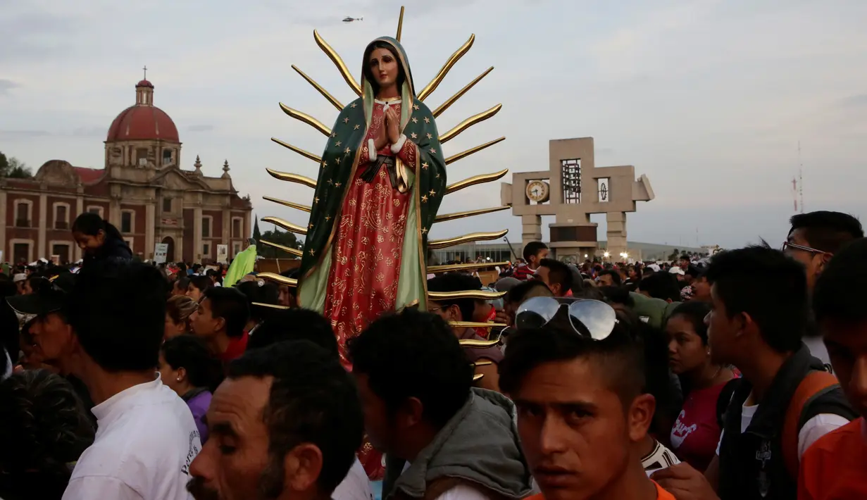 Sebuah patung Bunda dari Guadalupe diantara kerumunan peziarah di kawasan Basilika Guadalupe di Mexico City, Meksiko (11/12). Bunda dari Guadalupe adalah penampakan sosok Maria paling tua yang tercatat dalam sejarah agama Katolik. (Reuters/Henry Romero)