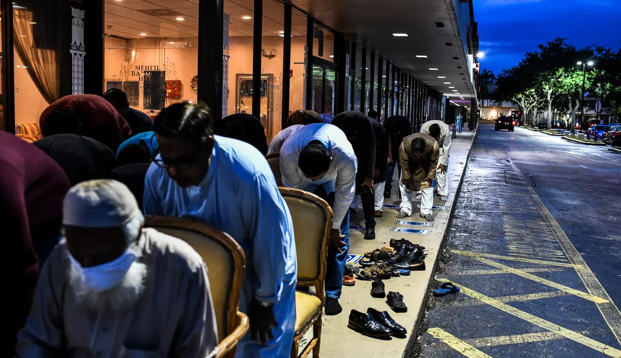 Pria Muslim melaksanakan salat di trotoar di luar restoran selama bulan suci Ramadhan di Lauderhill, Florida, Jumat (30/4/2021). Selama puasa Ramadhan, umat Islam tidak makan, minum, atau aktivitas seksual dari fajar hingga matahari terbenam. (CHANDAN KHANNA/AFP)