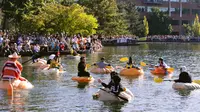 Peserta menaiki labu raksasa berkumpul di garis start selama  event West Coast Giant Pumpkin Regatta di Tualatin, Oregon, Amerika Serikat pada 16 Oktober 2022. Dalam perlombaan ini, para peserta akan dituntut untuk mendayung sepanjang 100 yard atau 91 meter. (Photo by Wesley Lapointe / AFP)