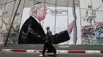 Seorang pria Palestina berjalan didepan grafiti yang menggambarkan Presiden AS Donald Trump di tembok pemisah Israel - Palestina di kota Bethlehem (4/8). Tembok di Tepi Barat ini membentang sepanjang 700 kilometer. (AFP Photo/Musa Al Shaer)