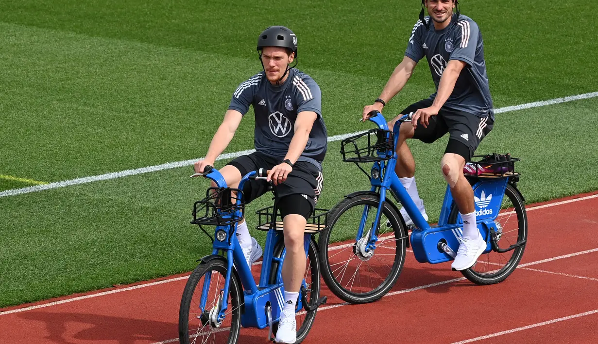 Bek Jerman Marcel Halstenberg (kiri) dan Mats Hummels (kanan) tiba dengan sepeda untuk sesi latihan latihan menjelang UEFA EURO 2020 di World of Sports Campus di Herzogenaurac (11/6/2021). Jerman berada di grup F Euro 2020 bersama Portugal, Prancis dan Hungaria. (AFP/Christof Stache)