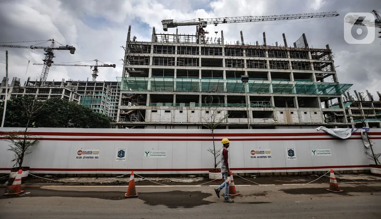 Pekerja melintas di depan proyek pembangunan rumah susun sewa (Rusunawa) PIK Pulogadung, Jakarta, Kamis (25/2/2021). Pemprov DKI Jakarta menargetkan proyek pembangunan 10 rusun rampung pada tahun 2021. (merdeka.com/Iqbal S. Nugroho)