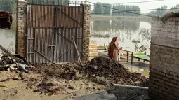 Seorang wanita berjalan di dekat rumah yang rusak setelah hujan lebat, di Charsadda, Pakistan, Rabu (31/8/2022). Para pejabat di Pakistan menyampaikan kekhawatiran Rabu atas penyebaran penyakit yang ditularkan melalui air di antara ribuan korban banjir saat air banjir dari hujan monsun yang kuat mulai surut di banyak bagian negara. (AP Photo/Mohammad Sajjad)