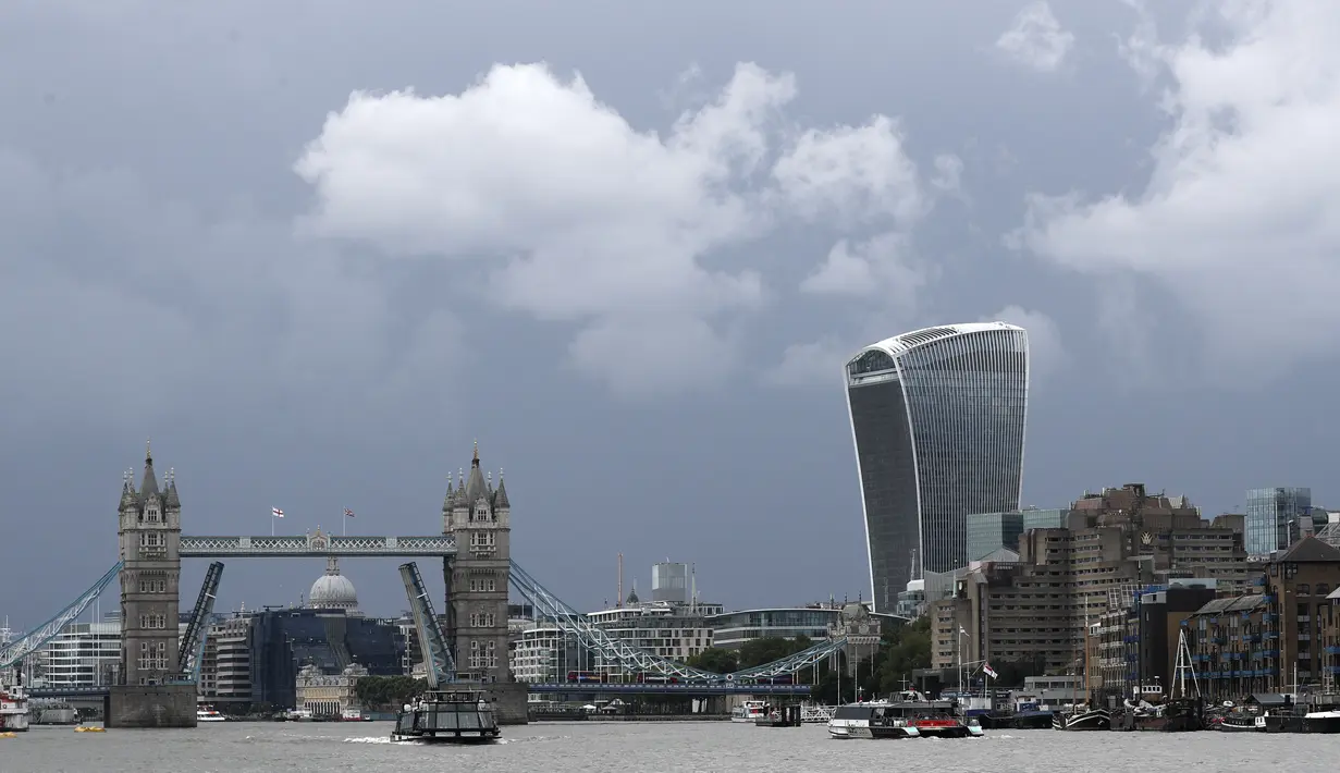 Perahu menyusuri Sungai Thames di depan Tower Bridge London yang terjebak dalam posisi terbuka penuh, Senin (9/8/2021). Tower Bridge London macet terbuka mengakibatkan gangguan lalu lintas di kedua sisi Sungai Thames karena mobil dan pejalan kaki tidak dapat menyeberang. (AP/Tony Hicks)