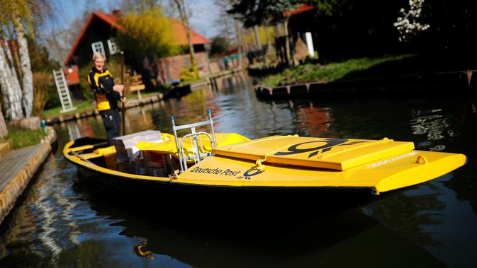 Tukang pos wanita dari Deutsche Pos DHL, Andrea Bunar menggunakan perahu tradisional untuk mengantar surat dan paket di desa Spreewald di Lehde, Jerman, 4 April 2019. Andrea Bunar menggunakan perahu untuk mengantar surat setiap bulan April hingga Oktober. (REUTERS/Hannibal Hanschke)