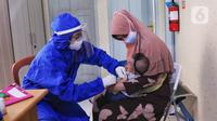 Bidan mengenakan alat pelindung diri (APD) saat melakukan imunisasi kepada bayi di Puskesmas Karawaci Baru, Tangerang, Banten, Rabu (13/5/2020). Pelayanan imunisai sesuai jadwal ini diberikan kepada bayi untuk menambah kekebalan imun tubuh. (Liputan6.com/Angga Yuniar)