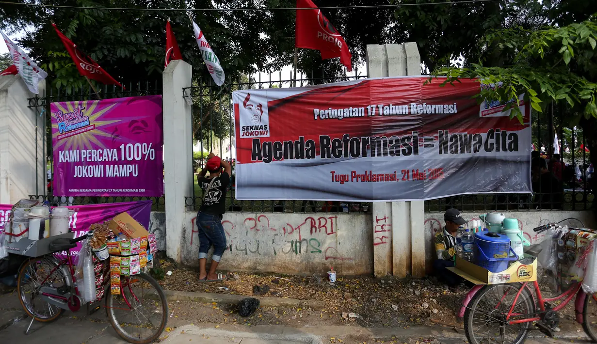 Pedagang berdiri di dekat spanduk yang berisi dukungan terhadap Jokowi, di sekitar Tugu Proklamasi, Jakarta, Kamis (21/5/2015). Spanduk tersebut dipasang dalam rangka memperingati 17 tahun reformasi. (Liputan6.com/Faizal Fanani)