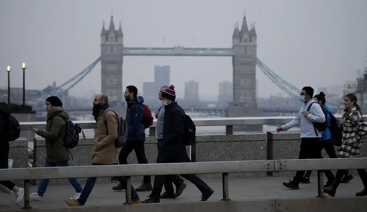 Pekerja berjalan di atas Jembatan London menuju distrik keuangan Kota London, dengan latar belakang Tower Bridge, pada jam sibuk pagi hari, Senin (24/1/2022). Inggris telah meminta orang-orang untuk kembali bekerja di kantor saat mereka melonggarkan pembatasan corona COVID-19. (AP Photo/Matt Dunham)