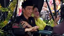 Presiden Joko Widodo bersama Ibu Negara Iriana menyapa warga saat kirab resepsi pernikahan Kahiyang Ayu-Bobby Nasution di Kota Medan, Sumatera Utara, Minggu (26/11). (Liputan6.com/Johan Tallo)