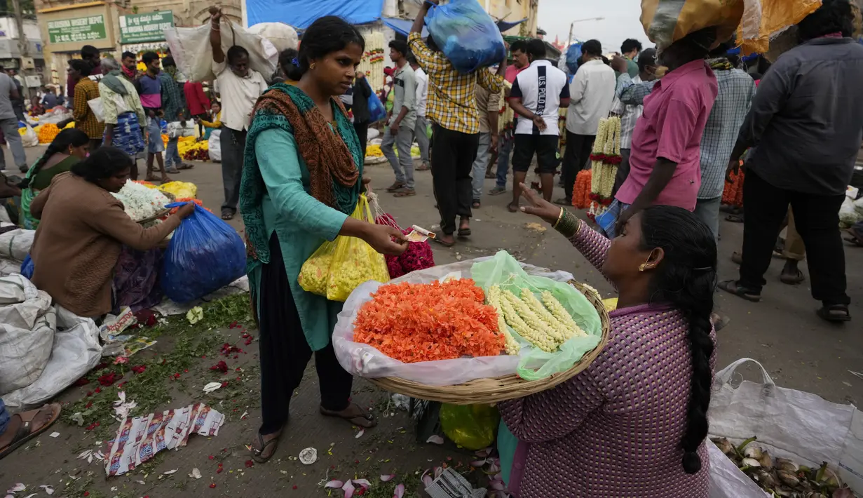 Seorang wanita menawar dengan penjual bunga di pasar grosir di Bengaluru, India, Rabu (13/4/2022). Orang-orang telah kembali beraktivitas normal setelah pihak berwenang mencabut pembatasan COVID-19 termasuk mengenakan masker wajah di tempat-tempat umum. (AP Photo/Aijaz Rahi)