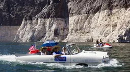Keluarga Baker menaiki mobil amfibi Amphicar 1965 saat festival Las Vegas Amphicar Swim di Danau Mead, Nevada, Jumat (9/10). (REUTERS/Steve Marcus)