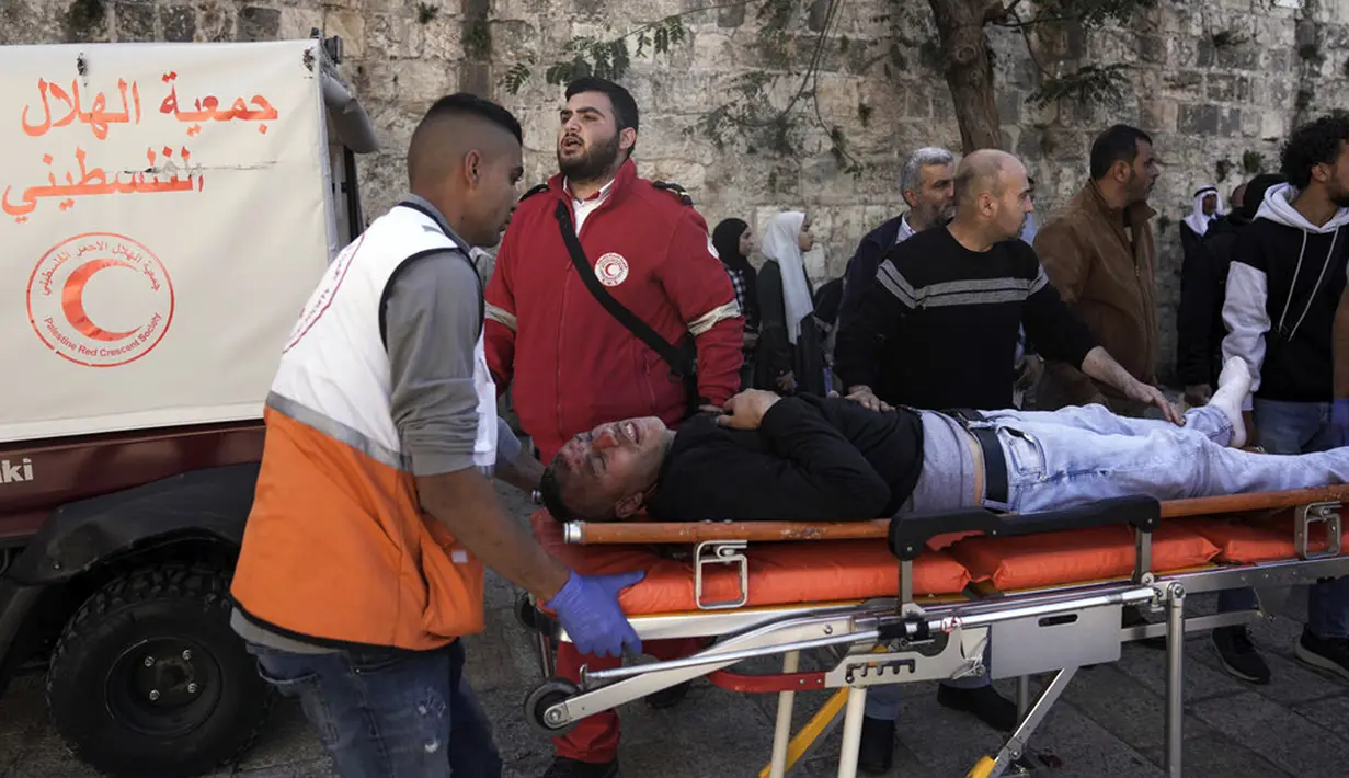 Petugas medis mengevakuasi seorang pria Palestina yang terluka dalam bentrokan antara demonstran Palestina dengan pasukan keamanan Israel di luar Kompleks Masjid Al Aqsa, Kota Tua Yerusalem, 15 April 2022. (AP Photo/Ariel Schalit)