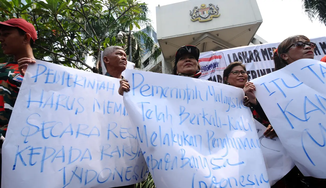 Peserta aksi membentangkan kertas pesan saat berunjuk rasa di depan Kedubes Malaysia, Jakarta, Senin (21/8). Aksi ini terkait kasus terbaliknya bendera Merah Putih pada buku panduan pelaksanaan SEA Games 2017. (Liputan6.com/Helmi Fithriansyah)