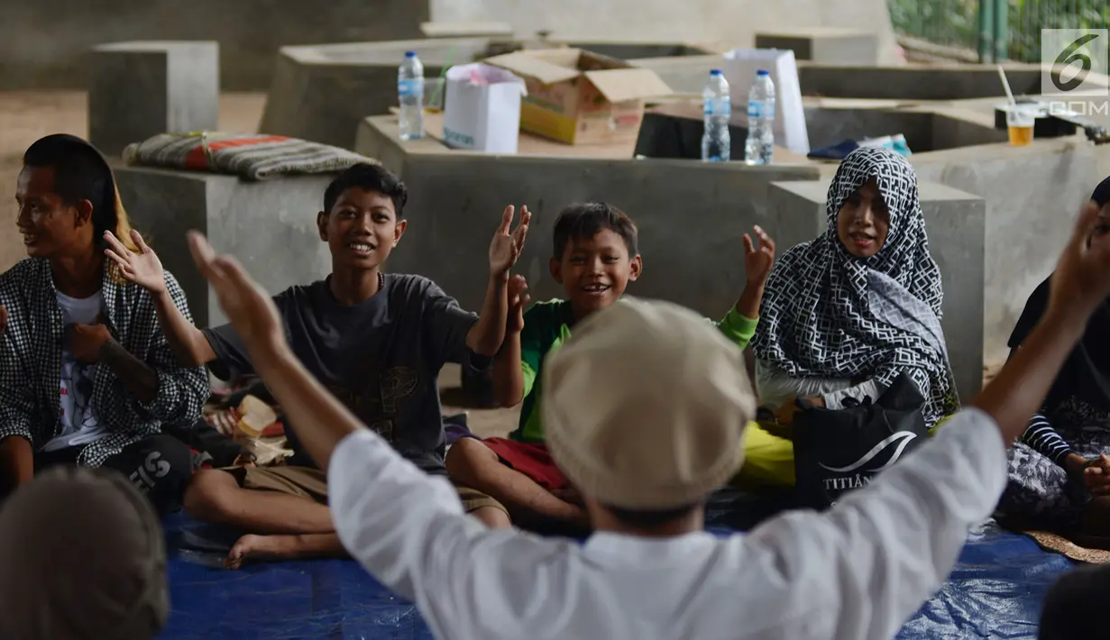 Guru memberikan bimbingan pada sekelompok anak punk yang sedang belajar mengaji dengan Komunitas Tasawuf Underground di kolong flyover Tebet, Jakarta, Sabtu (8/12). (Merdeka.com/Imam Buhori)