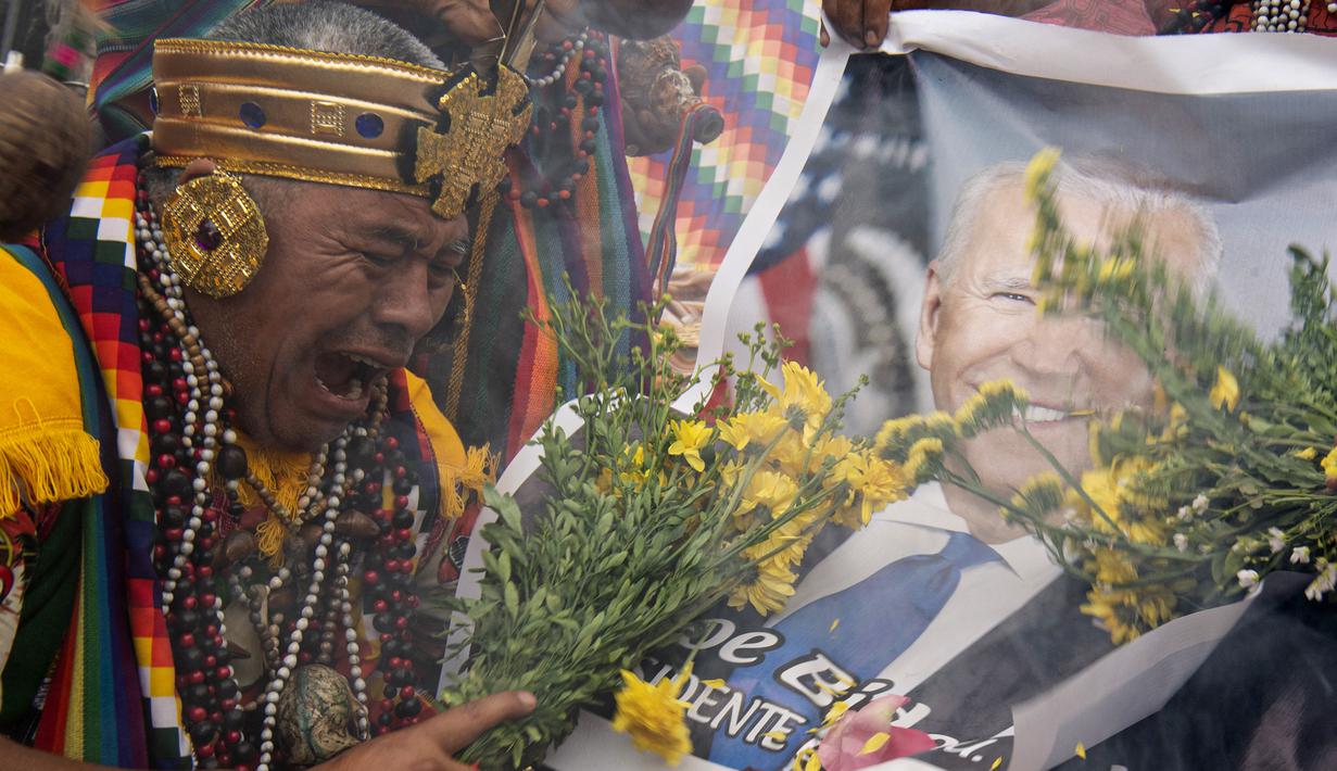 Dukun Peru memegang foto Presiden Meksiko Andres Manuel Lopez Obrador saat memberikan prediksi untuk 2022 dalam ritual tradisional sebelum Malam Tahun Baru di bukit San Cristobal di Lima, Peru (29/12/2021). (AFP/Ernesto Benavides)
