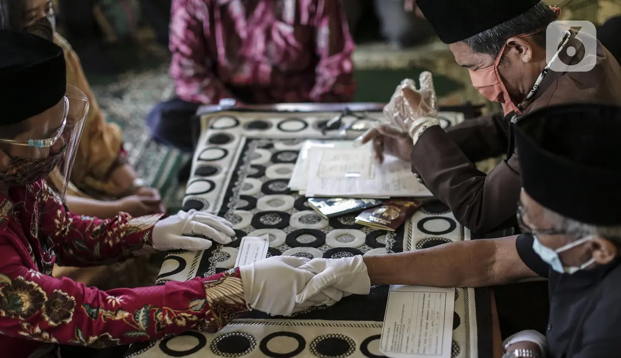 Pasangan pengantin menjalani prosesi akad nikah di KUA Pondok Pinang, Kebayoran Lama, Jakarta, Jumat (17/7/2020). Di masa PSBB transisi, pihak KUA menikahkan 8-10 pasangan per hari dengan mengikuti protokol kesehatan sesuai Surat Edaran Menteri Agama Nomor 15 Tahun 2020. (Liputan6.com/Johan Tallo)
