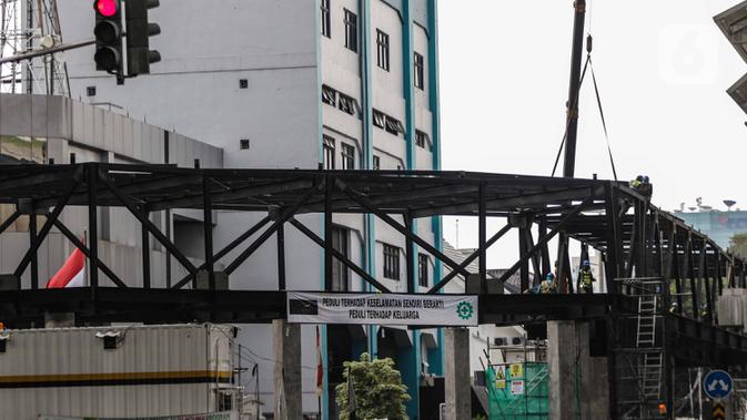 Pekerja menyelesaikan jembatan layang integrasi antara Stasiun MRT ASEAN dengan Halte Transjakarta CSW koridor 13, Jakarta, Rabu (8/1/2020). Jembatan layang ini nantinya akan memudahkan penumpang untuk mengakses salah satu moda transportasi baik MRT atau Transjakarta. (Liputan6.com/Faizal Fanani)