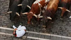 Seorang pengunjung festival terjatuh di depan banteng-banteng aduan Victoriano del Río saat acara lari banteng ketiga di festival San Fermín di Pamplona, Spanyol, Kamis, 9 Juli 2026. (AP Photo/Miguel Oses)