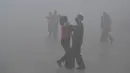 Warga mengenakan masker menari saat kabut tebal menyelimuti Fuyang, Provinsi Anhui, China, 3 Januari 2017. (China Daily/via Reuters)