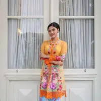 Erina Gudono tampil anggun dalam balutan kebaya encim berwarna oranye motif penari dipadu kain batik Betawi berwarna sky blue. Penampilannya dipermanis dengan anting dan kalung mutiara. [Instagram/erinagudono]