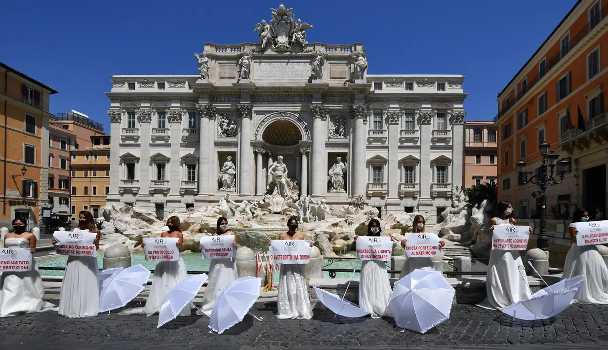 Pengantin perempuan yang mengenakan gaun pernikahan mereka melakukan protes dengan flashmob di Trevi Fountain, Roma, Selasa (7/7/2020). Mereka memprotes kebijakan pemerintah Italia yang masih melarang adanya acara pernikahan, meski penerapan lockdown sudah dilonggarkan. (Tiziana FABI/AFP)