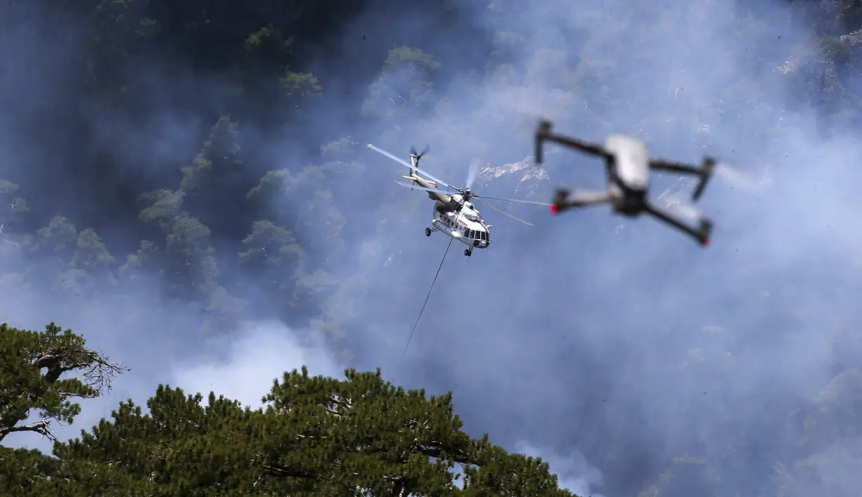 Sebuah helikopter berpartisipasi dalam operasi pemadaman kebakaran hutan di Koycegiz, Mugla, Turki, Senin (9/8/2021). Kebakaran hutan memaksa warga melarikan diri ke pantai untuk diselamatkan melalui laut. (AP Photo/Emre Tazegul)
