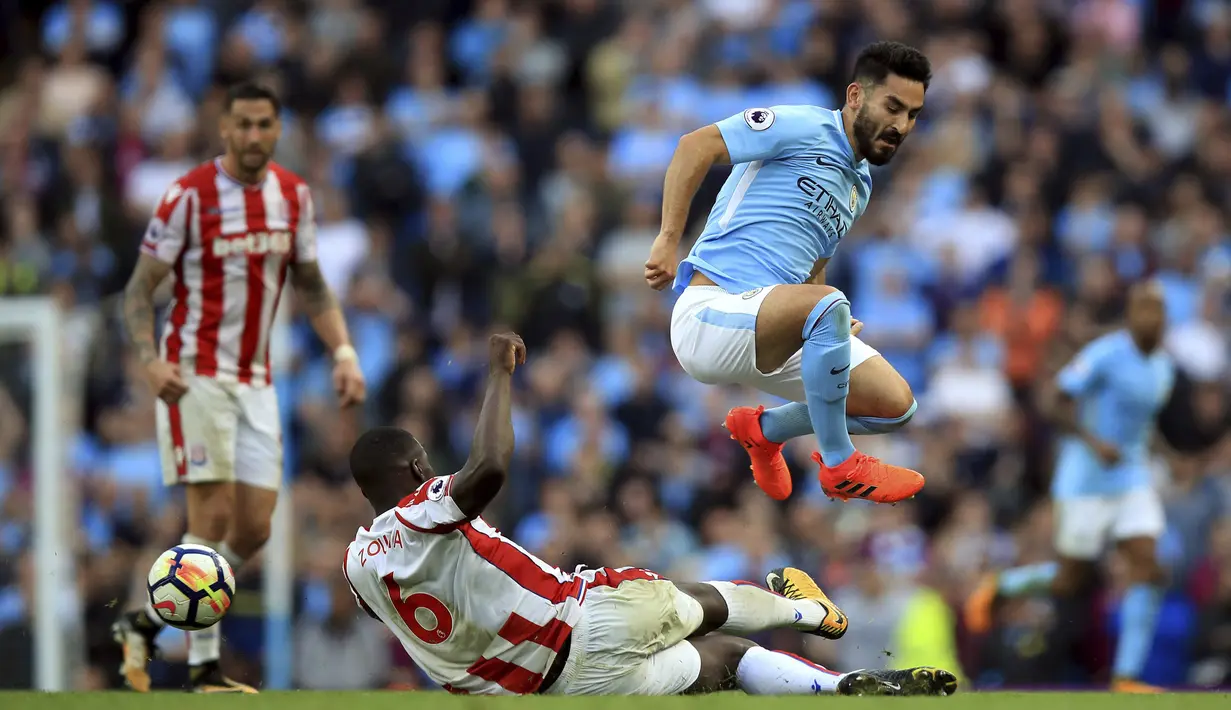 Pemain Stoke City, Kurt Zouma (kiri) menghalau bola dari kejaran pemain Manchester City, Ilkay Gundogan pada lanjutan Premier League di Etihad Stadium, Manchester, (14/10/2017). City menang 7-2. (Mike Egerton/PA via AP)