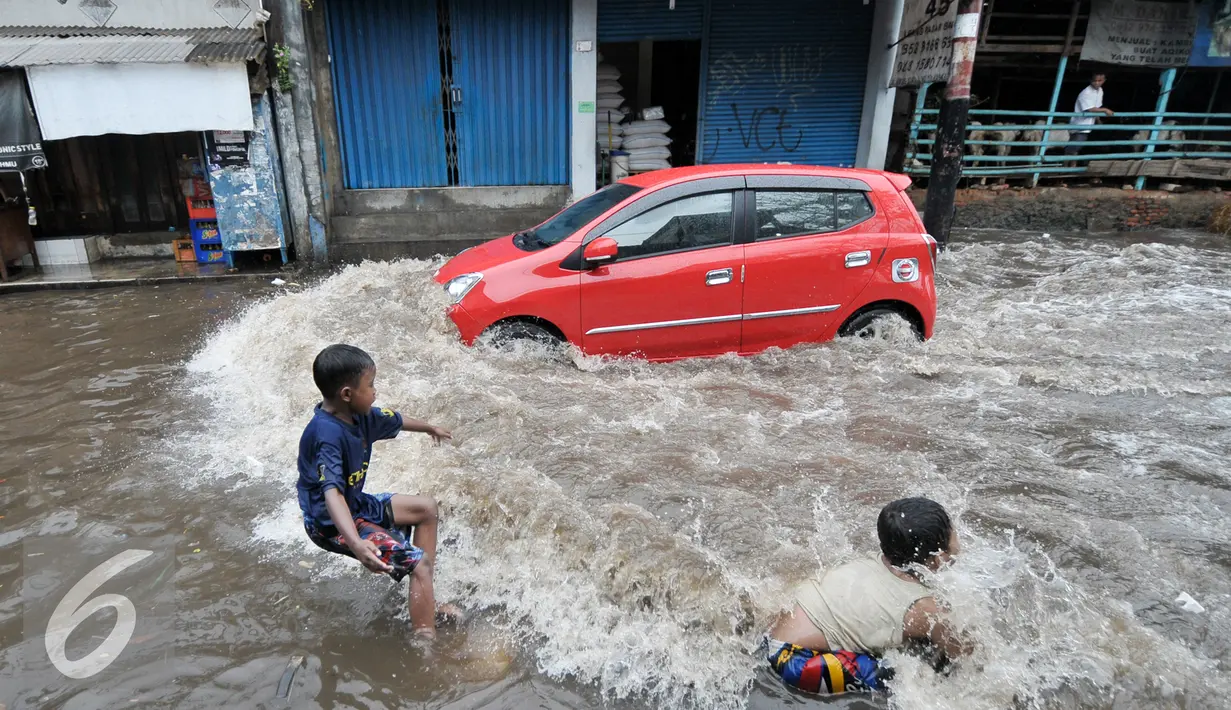 Sejumlah anak bermain dengan gelombang air yang terdorong oleh kendaraan saat melintasi banjir, Jakarta, Rabu (20/7). Akibat hujan deras kawasan Kemang Utara tergenang air 60cm sampai 1 meter. (Liputan6.com/Yoppy Renato)