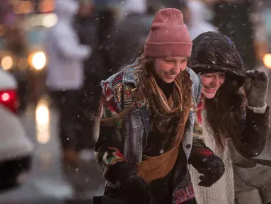 Pejalan kaki melintasi persimpangan di Times Square saat badai salju di New York City (7/3). Badai salju kedua yang melanda New York dalam waktu seminggu ini diperkirakan akan membawa angin kencang. (Drew Angerer/Getty Images/AFP)