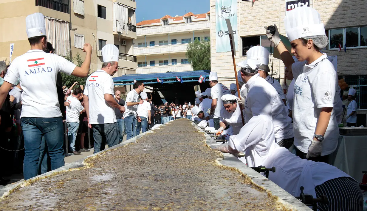 Peserta menyiapkan roti manousheh dengan rempah-rempah, wijen dan minyak zaitun, di Choueifat, Beirut, Lebanon (22/11). Roti sepanjang 32 meter ini disiapkan untuk memperingati Hari Kemerdekaan Lebanon dengan tujuan memecahkan rekor dunia. (AFP PHOTO/STR)