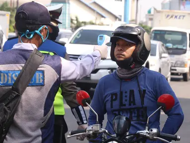 Petugas memeriksa suhu tubuh pengendara saat pelaksanaan Pembatasan Sosial Berskala Besar (PSBB) di kawasan Gading Serpong, Tangerang Selatan, Sabtu (18/4/2020). Pengukuran suhu tubuh tersebut merupakan cek point dari PSBB yang baru saja diberlakukan di Tangerang Raya. (Liputan6.com/Angga Yuniar)