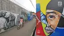 Seorang bocah bermain sepeda di antara dinding berhias mural bertema Islami di Gang Abdul Jabar, Jagakarsa, Jakarta, Senin (28/5). (Liputan6.com/Herman Zakharia)