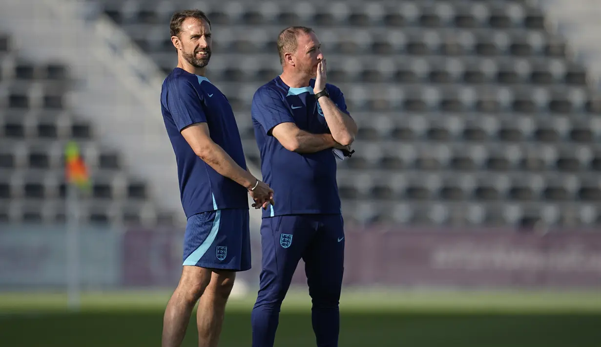 Pelatih Inggris,  Gareth Southgate (kiri) dan asisten Steve Holland menyaksikan pemainnya berlatih selama sesi latihan di Kompleks Olahraga Al Wakrah di Al Wakarah, Qatar, Senin, 28 November 2022.  Saat ini, Inggris memimpin di puncak klasemen dengan raihan 4 poin dari dua laga. Sementara Wales berada di posisi terakhir yang baru meraih satu poin. (AP Photo/Abbie Parr)