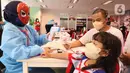 Petugas medis mengenakan topeng superhero mengecek kesehatan anak sebelum menyuntikkan vaksin Sinonvac kepada anak-anak saat mengikuti vaksinasi ke dua di Gedung  OJK, Jakarta, Minggu (16/01/2022). Sebanyak 350 anak karyawan OJK mengikuti vaksinasi Covid-19 dosis kedua. (Liputan6.com/Angga Yuniar)