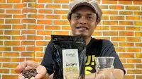 Pemilik kedai Kopilink, Takdir Hamzah yang memperlihatkan biji kopi Sota Merauke. (Foto: Liputan6.com / KabarPapua.co / Abdel Syah)