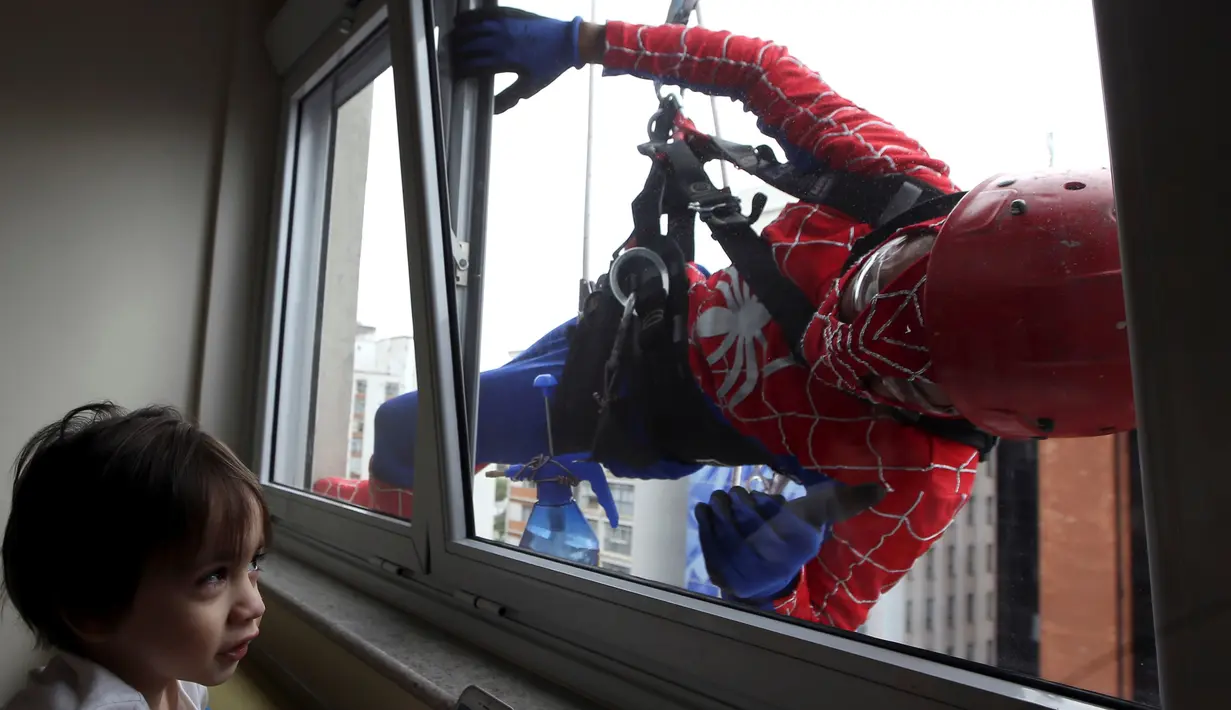 Petugas pembersih kaca berkostum Spiderman bercanda dengan salah satu pasien anak yang dirawat di RS Infantil Sabara, Sao Paulo, Senin (10/10). Aksi ini bagian dari perayaan Hari Anak Brasil yang diperingati setiap 12 Oktober. (REUTERS/Paulo Whitaker)