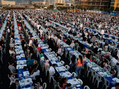 Warga Lebanon beserta yatim piatu dan pengungsi Suriah  berkumpul di sekitar meja-meja Iftar di Beirut Waterfront, Lebanon (9/6). Sebuah organisasi amal Lebanon menggelar buka puasa Ramadan dengan meja terpanjang di dunia. (AP Photo / Hussein Malla)