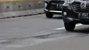 Kendaraan melintas di dekat jalan berlubang di Jalan Jenderal Sudirman, Jakarta, Senin (11/3). Minimnya perawatan dan pengawasan membuat jalan tersebut berlubang hingga kedalaman 10 sentimeter. (merdeka.com/Iqbal S. Nugroho)