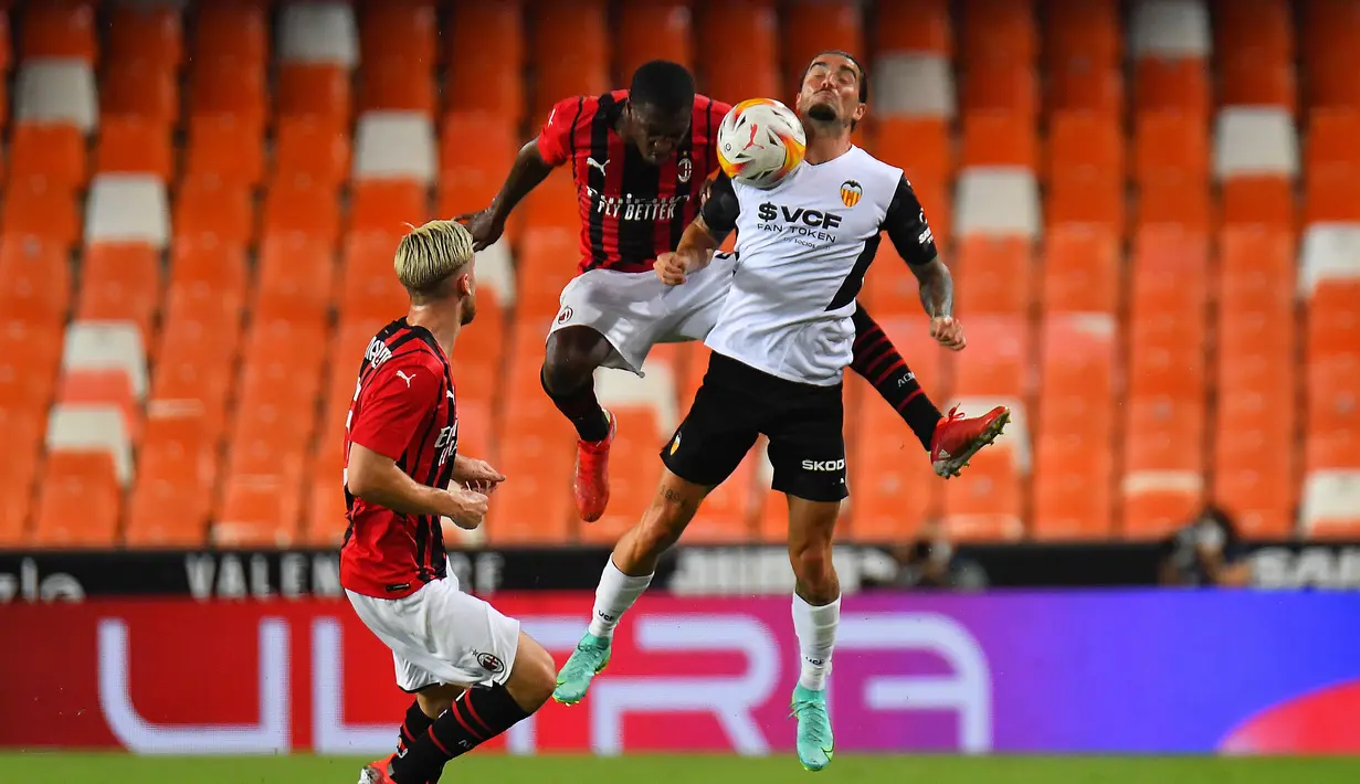 Bek AC Milan, Fode Ballo-Toure (tengah) berebut bola dengan gelandang Valencia, Jason (kanan) selama pertandingan persahabatan di Stadion Mestalla di Valencia (4/8/2021). Bermain imbang 0-0 di waktu normal, AC Milan kalah atas Valencia lewat adu penalti 5-3. (AFP/Jose Jordan)