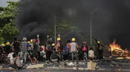 Para pengunjuk rasa berlindung di balik perisai buatan sendiri saat mereka menghadapi polisi selama tindakan keras terhadap demonstrasi menentang kudeta militer di Yangon, Myanmar, 16 Maret 2021. (STR/AFP)