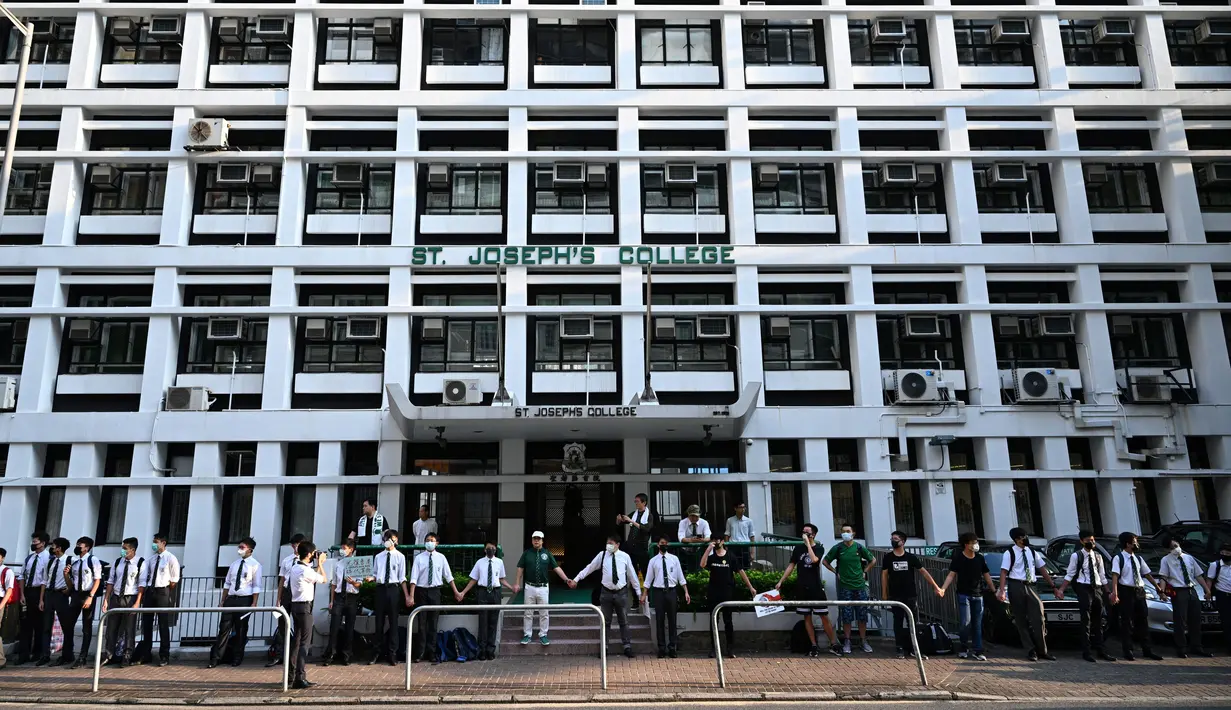 Para siswa, alumni dan guru saling memegang tangan di area Mid-Levels, Hong Kong, Senin (9/9/2019). Aksi dilakukan para siswa yang masih berseragam sekolah sambil memakai masker sebagai bentuk dukungan terhadap demonstran anti pemerintah setelah bentrokan pada akhir pekan. (Anthony WALLACE/AFP)