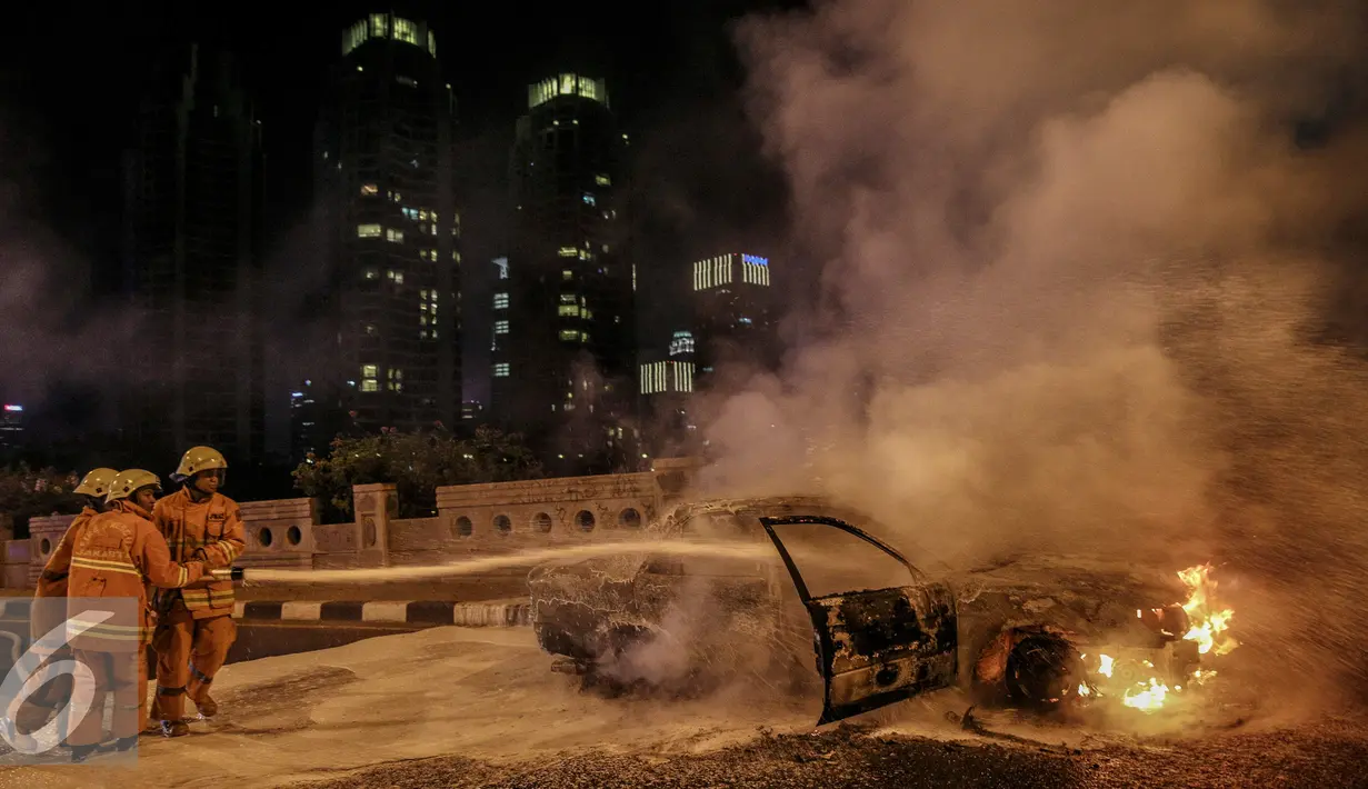 Petugas berusaha memadamkan api mobil yang terbakar di jalan layang Latuharhari, Jakarta, Kamis (18/9/2015). Diduga kebakaran akibat konsleting listrik yang terjadi dibagian depan kap mobil. (Liputan6.com/Faizal Fanani)