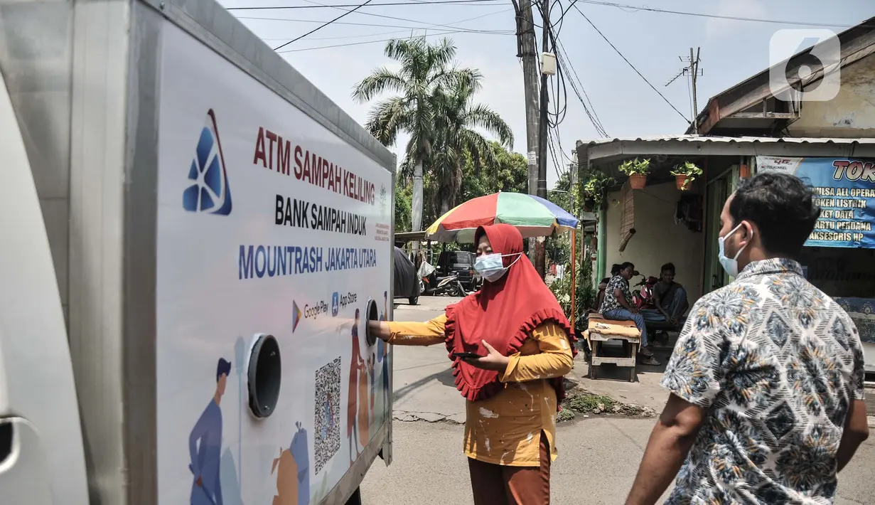 Warga memasukkan sampah saat menabung di ATM Sampah Keliling di Semper Barat, Cilincing, Jakarta Utara, Selasa (12/10/2021). Tiap warga atau nasabah nantinya diberikan rekening melalui aplikasi smartphone sebagai bukti menabung sampah yang dapat dicairkan menjadi uang. (merdeka.com/Iqbal S. Nugroho)