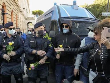 Demonstran membawa bunga untuk petugas polisi selama aksi protes di Circus Maximus Roma, Jumat (15/10/2021). Protes tersebut karena aturan yang mengharuskan seluruh pekerja di Italia menunjukkan kartu kesehatan covid-19 untuk memasuki tempat kerja mereka. (AP Photo/Gregorio Borgia)