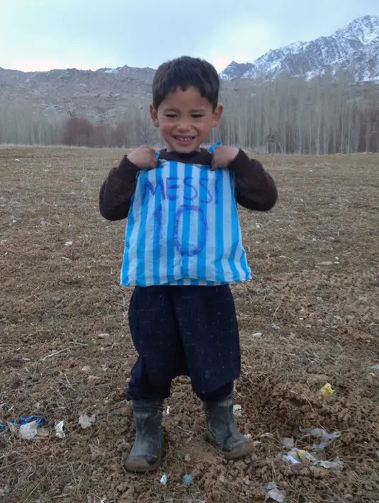 Murtaza Ahmadi (5) mengenakan kostum timnas Argentina milik Lionel Messi yang terbuat dari kantong kresek di  kabupaten Jaghori, Afghanistan, 29 Januari 2016. Karena situasi ekonomi, keluarga tak mampu membelikan Murtaza jersey Messi. (STR/AFP)