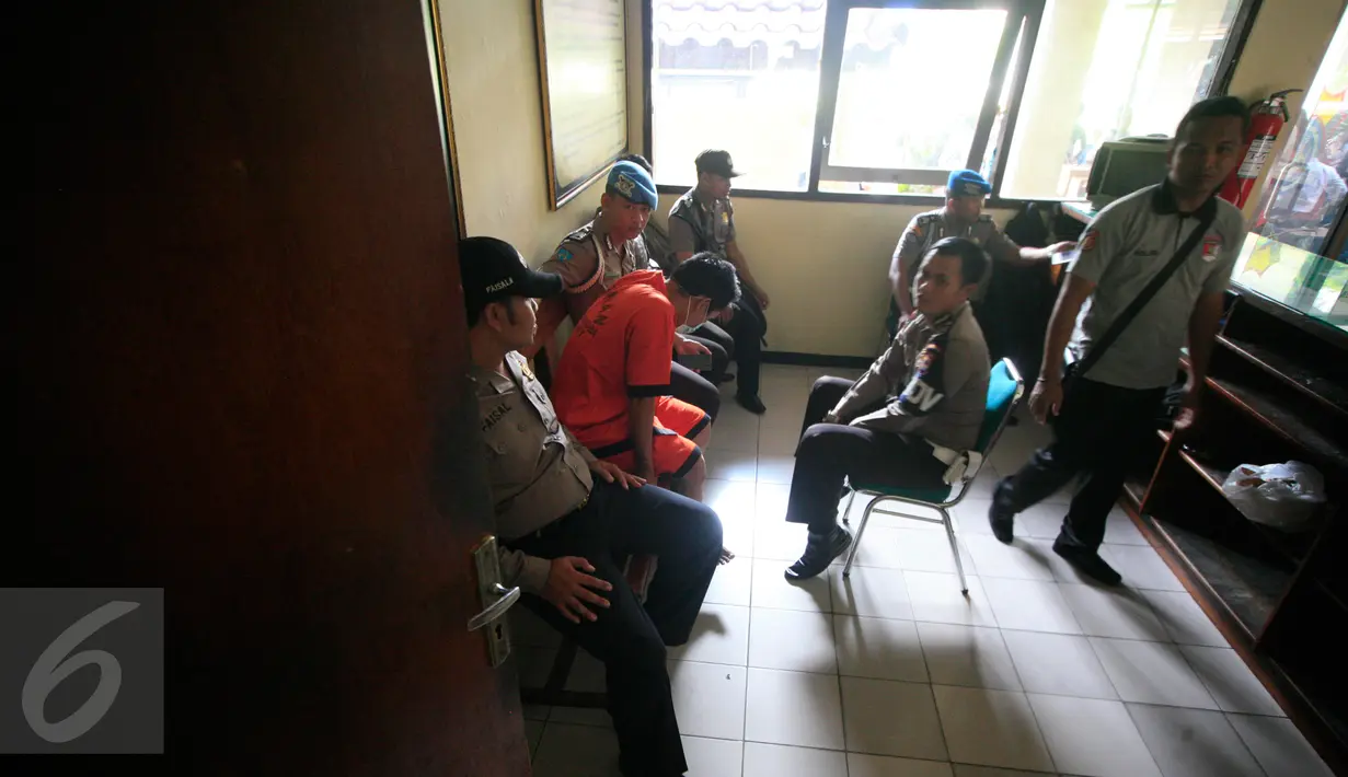 Ismail (47) yang merupakan tersangka pencabulan duduk diantara petugas kepolisian di Mapolda DIY, Selasa (17/5). Kepala Sekolah Madrasah Aliyah di Bantul itu tega mencabuli siswi kelas tiga MTs berinisial S (16) hingga hamil. (Liputan6.com/Boy Harjanto)