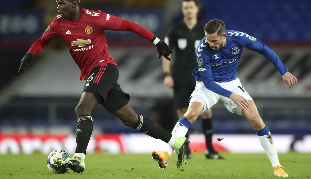 Gelandang Manchester United, Paul Pogba menggiring bola dari kawalan pemain Everton, Gylfi Sigurdsson babak perempat final di Goodison Park, Kamis (24/12/2020). MU tampil dominan di babak pertama. Namun tak ada gol yang tercipta selama 45 menit pertama. (AP Photo/Nick Potts,Pool)