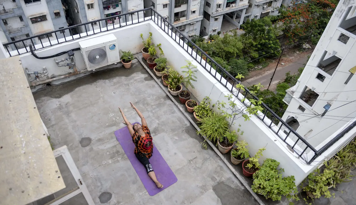 Instruktur yoga Pratibha Agarwal dari Anahata Yoga Zone melakukan gerakan yoga menjelang Hari Yoga Internasional di teras sebuah bangunan di Hyderabad, India pada 18 Juni 2020. Hari Yoga Internasional atau International Day of Yoga diperingati setiap tahun pada 21 Juni. (Photo by NOAH SEELAM / AFP)
