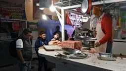 Orang-orang membeli daging di kios daging yang hampir habis di Pasar Rodriguez, La Paz, 16 November 2019. Pemblokiran jalan yang dilakukan pendukung mantan Presiden Bolivia Evo Morales membuat kelangkaan bahan makanan, terutama daging dan telur, mulai sulit ditemukan di pasar. (AIZAR RALDES/AFP)